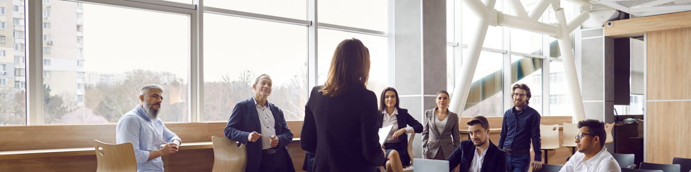 Réunion, une femme en tenue professionelle de dos parle à une équipe.
