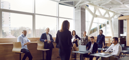 Réunion, une femme en tenue professionelle de dos parle à une équipe.