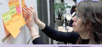 Jeune femme face à un tableau de post-it pour imaginer l’Ecole de demain, NEOMA Business School
